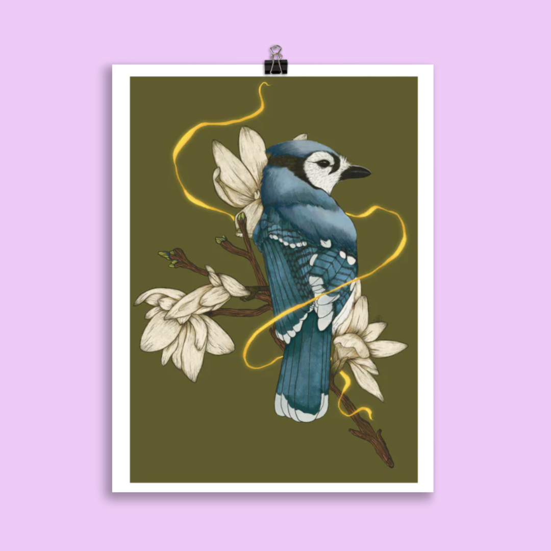 A print of a blujay sitting on a magnolia branch in front a dark green background, a gold glowing ribbon weaves around the bird and branch